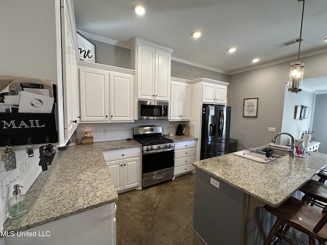 kitchen featuring stainless steel appliances, a kitchen breakfast bar, backsplash, a kitchen island with sink, and white cabinets