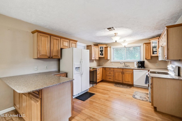 kitchen with a textured ceiling, white appliances, sink, kitchen peninsula, and light hardwood / wood-style flooring