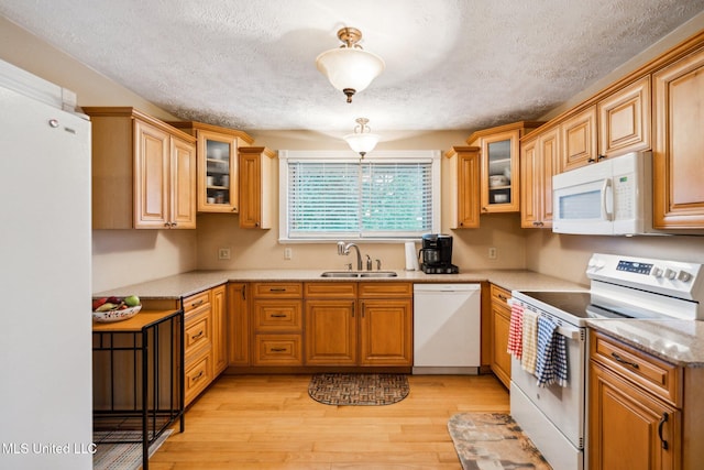 kitchen with white appliances, a textured ceiling, sink, and light hardwood / wood-style floors