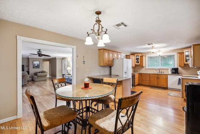 dining space with a textured ceiling, light hardwood / wood-style floors, and ceiling fan with notable chandelier