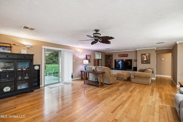 living room featuring ceiling fan, a textured ceiling, light hardwood / wood-style flooring, and crown molding