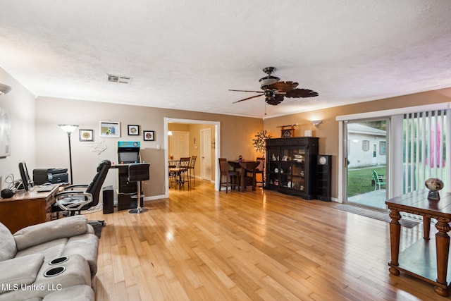 living room featuring ceiling fan, a textured ceiling, and light hardwood / wood-style floors