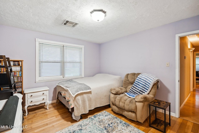 bedroom with a textured ceiling and light wood-type flooring