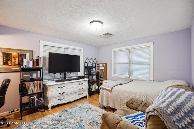 bedroom featuring a textured ceiling and light hardwood / wood-style floors