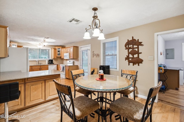 dining room with electric panel, a textured ceiling, sink, an inviting chandelier, and light hardwood / wood-style flooring