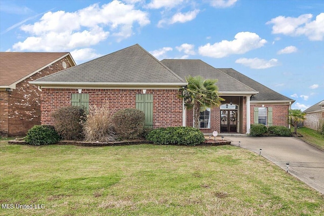 view of front of home featuring a shingled roof, a front yard, french doors, and brick siding