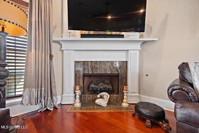 living area featuring wood finished floors, a high end fireplace, and baseboards