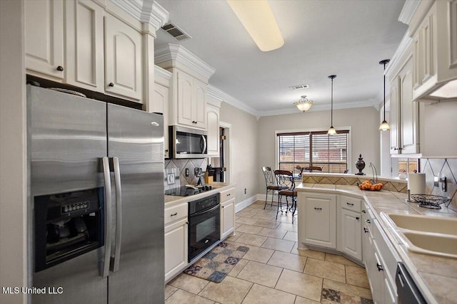 kitchen with decorative backsplash, white cabinets, hanging light fixtures, and black appliances