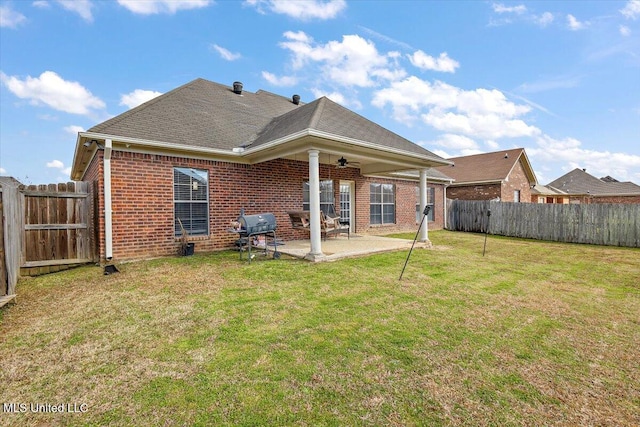 rear view of property featuring brick siding, a patio, a lawn, ceiling fan, and a fenced backyard