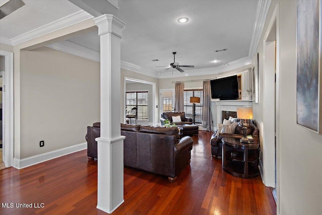 living area with dark wood-style flooring, a fireplace, ornate columns, ceiling fan, and baseboards