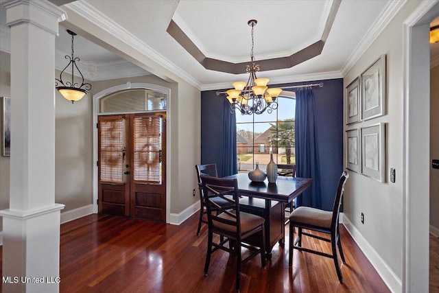 dining area with ornate columns, baseboards, dark wood-style floors, and a tray ceiling