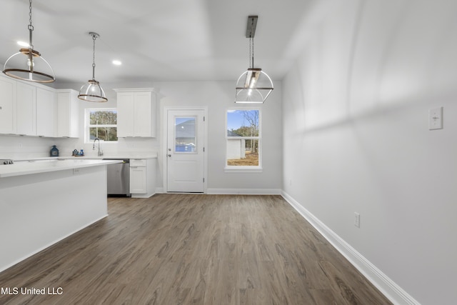 kitchen featuring white cabinetry, wood-type flooring, dishwasher, and pendant lighting