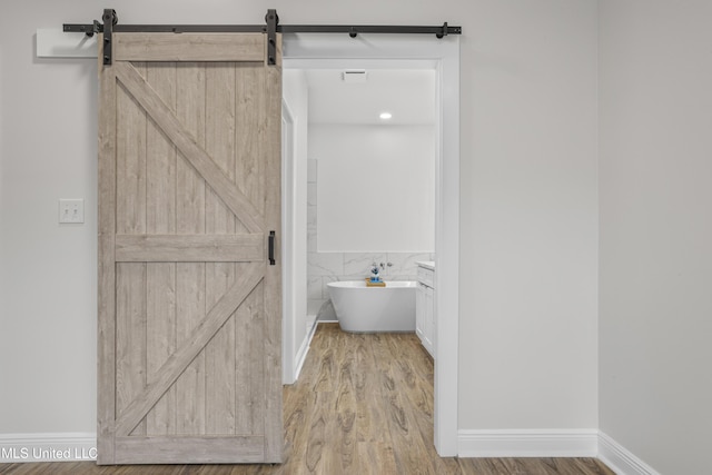 bathroom with hardwood / wood-style flooring, vanity, and a tub