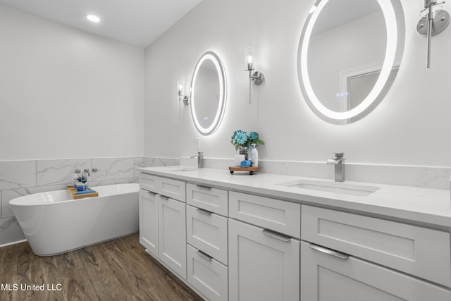 bathroom with wood-type flooring, tile walls, vanity, and a washtub