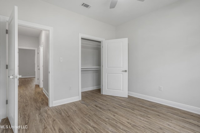 unfurnished bedroom featuring ceiling fan, a closet, and light wood-type flooring