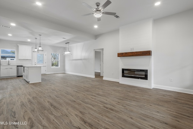 unfurnished living room featuring ceiling fan, a fireplace, and wood-type flooring