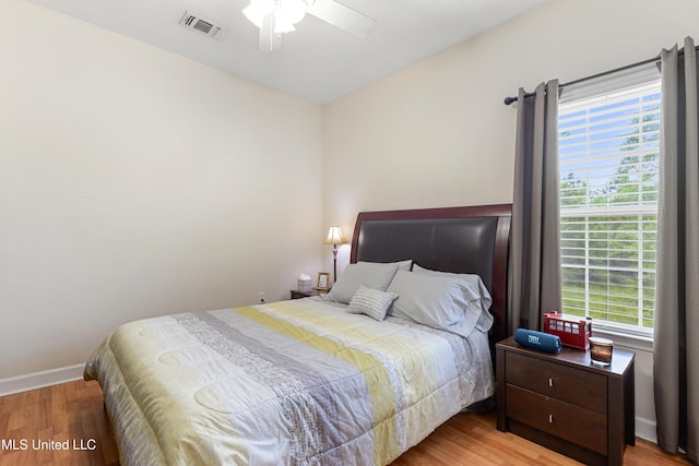 bedroom with a ceiling fan, visible vents, light wood-style flooring, and baseboards