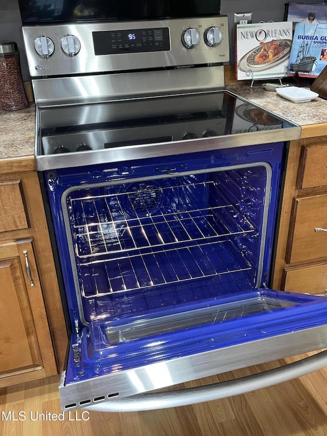 interior details featuring stainless steel range with electric stovetop and brown cabinets