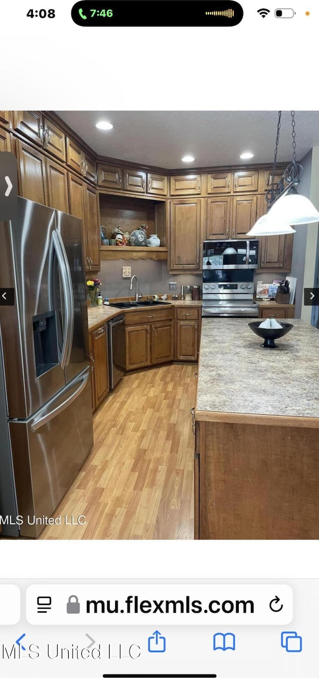 kitchen featuring a sink, light countertops, appliances with stainless steel finishes, open shelves, and light wood finished floors