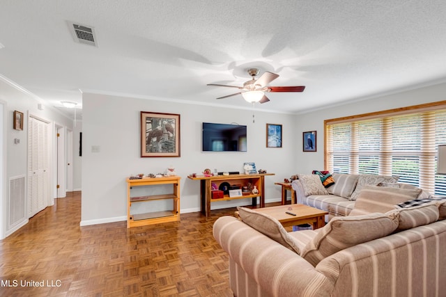 living area featuring a ceiling fan, a textured ceiling, baseboards, ornamental molding, and visible vents