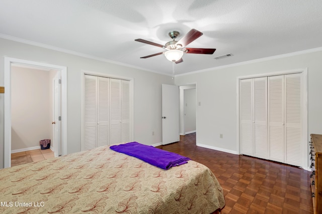 bedroom featuring ornamental molding, multiple closets, and visible vents