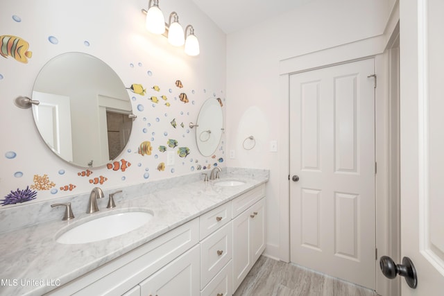 bathroom with double vanity, wood finished floors, and a sink