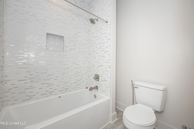 bathroom with tiled shower / bath combo and toilet