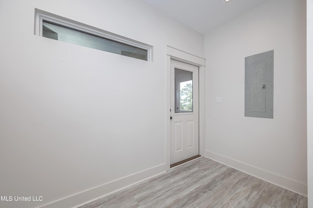 unfurnished room with light wood-style flooring, electric panel, and baseboards