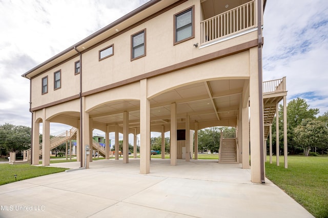 view of property's community featuring concrete driveway, a yard, and stairs