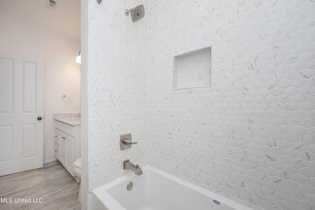 full bathroom featuring toilet, hardwood / wood-style floors, vanity, and tiled shower / bath combo