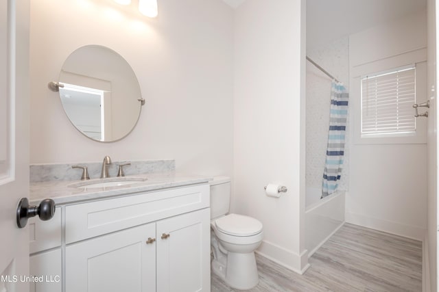 bathroom with baseboards, toilet, shower / tub combo with curtain, wood finished floors, and vanity