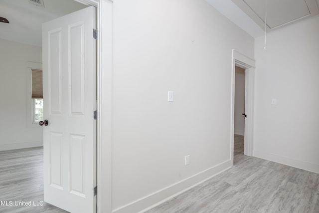 empty room featuring attic access, baseboards, and wood finished floors