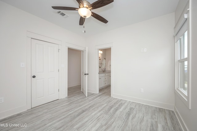 unfurnished bedroom featuring connected bathroom, a ceiling fan, visible vents, baseboards, and light wood-type flooring