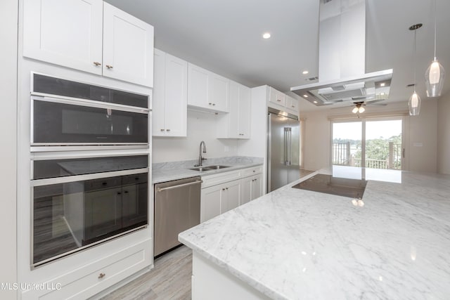 kitchen featuring white cabinetry, island range hood, stainless steel appliances, and a sink