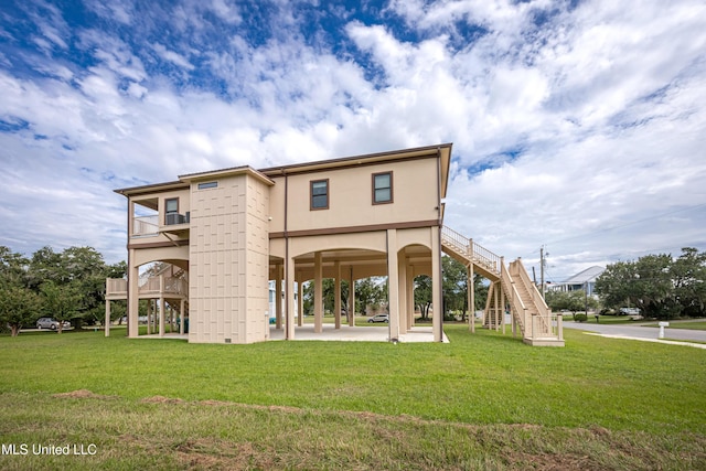 back of property with a balcony, a yard, and a patio