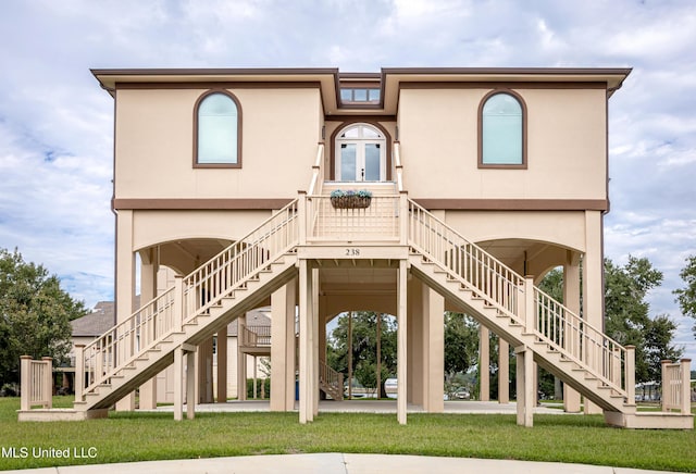 rear view of property featuring stairs, french doors, a lawn, and stucco siding