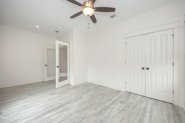 unfurnished bedroom featuring light wood-style floors, baseboards, visible vents, and a closet