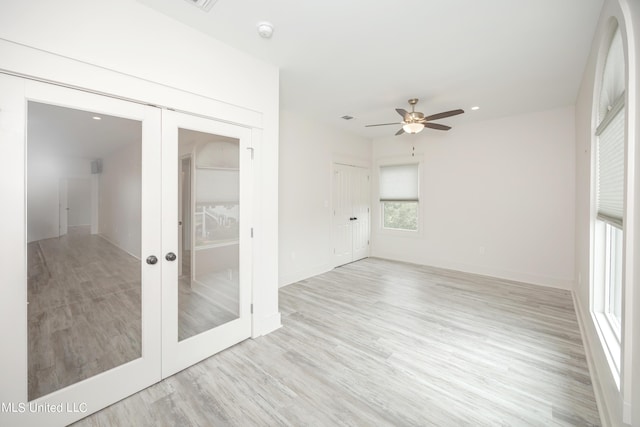 empty room with ceiling fan, french doors, and light wood-type flooring