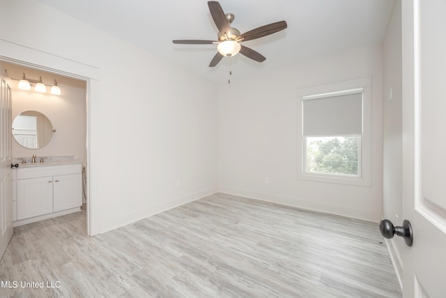 unfurnished room with light wood-style floors, ceiling fan, baseboards, and a sink