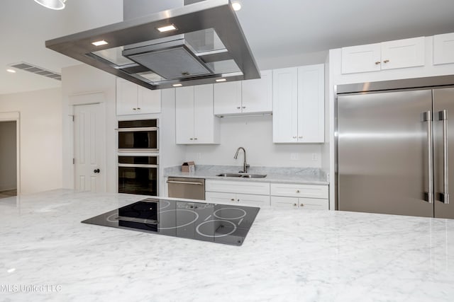 kitchen with light stone counters, visible vents, a sink, ventilation hood, and black appliances