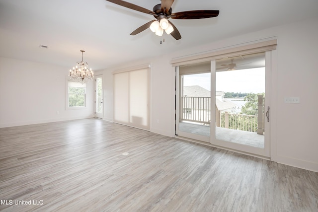 spare room featuring baseboards, visible vents, light wood finished floors, and ceiling fan with notable chandelier