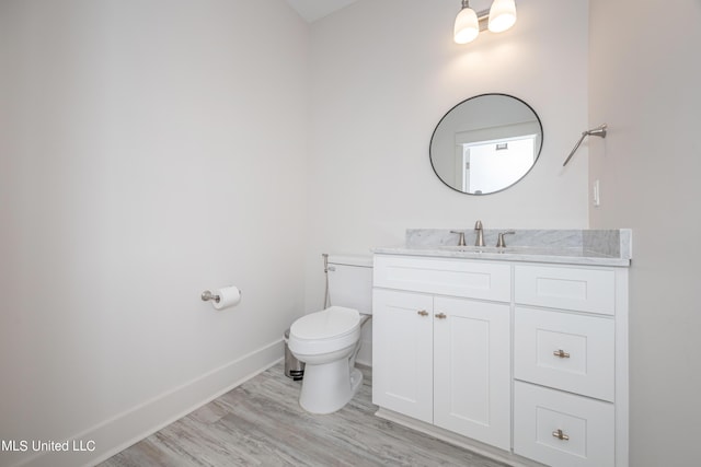 bathroom with vanity, wood finished floors, toilet, and baseboards