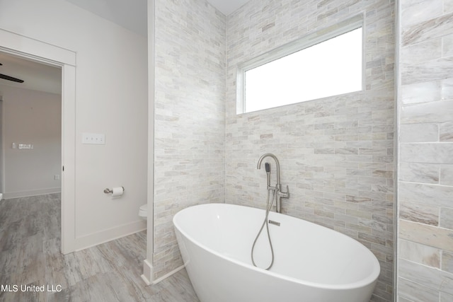 bathroom featuring a tub to relax in, toilet, and hardwood / wood-style flooring