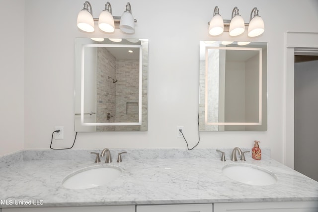 bathroom with double vanity, a sink, and tiled shower