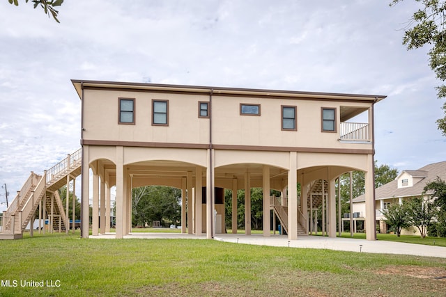 rear view of house featuring a yard, a carport, stairway, and concrete driveway