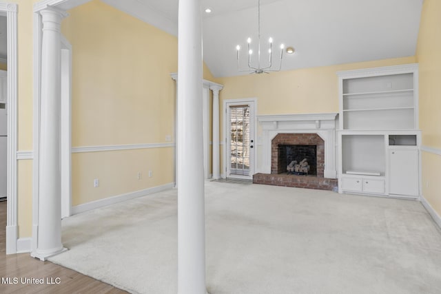 unfurnished living room featuring an inviting chandelier, vaulted ceiling, carpet floors, a fireplace, and decorative columns