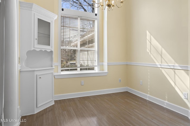 unfurnished dining area featuring an inviting chandelier and wood-type flooring