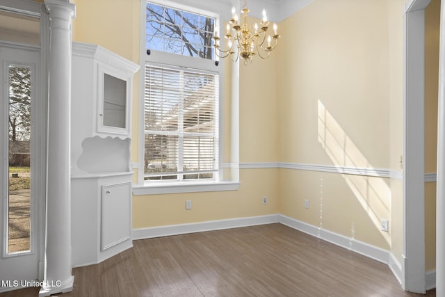 unfurnished dining area with wood-type flooring and an inviting chandelier