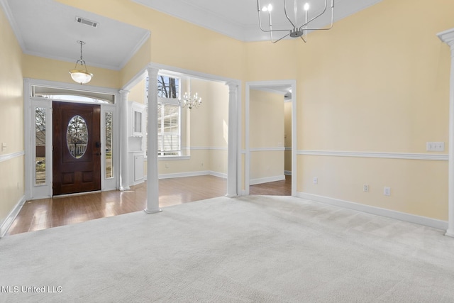 carpeted entryway with crown molding, a chandelier, and decorative columns