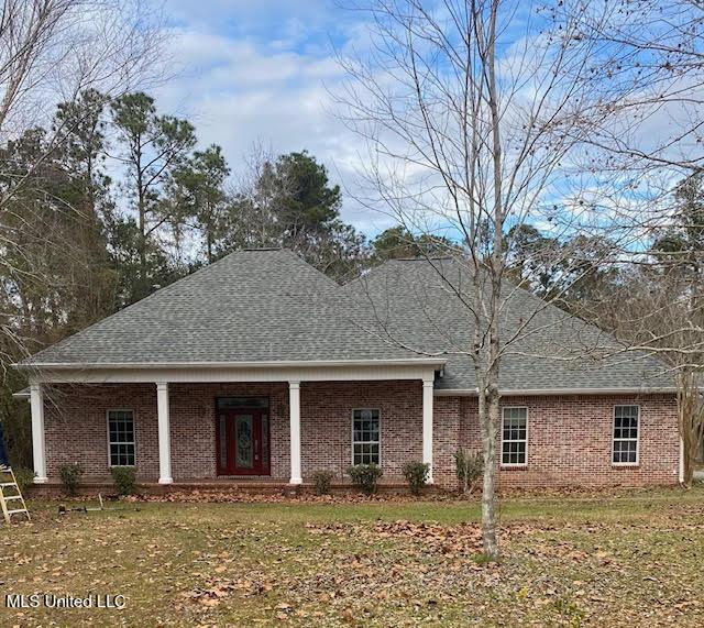 view of front of home with brick siding, roof with shingles, covered porch, and a front yard